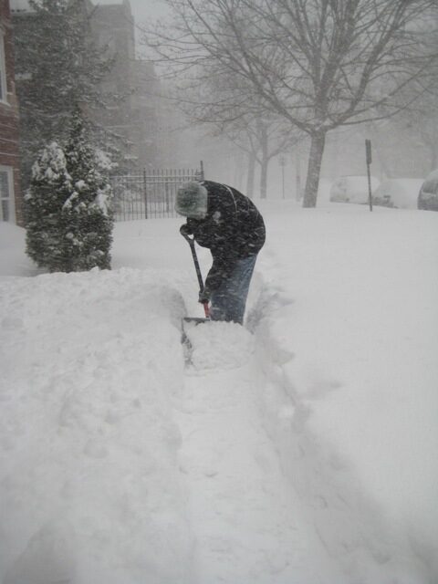 Ein Mann im Schneegestöber beim Schneeräumen.